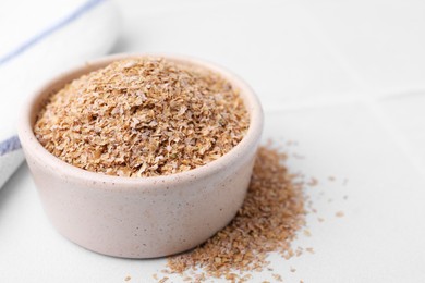 Buckwheat bran in bowl on white table, closeup