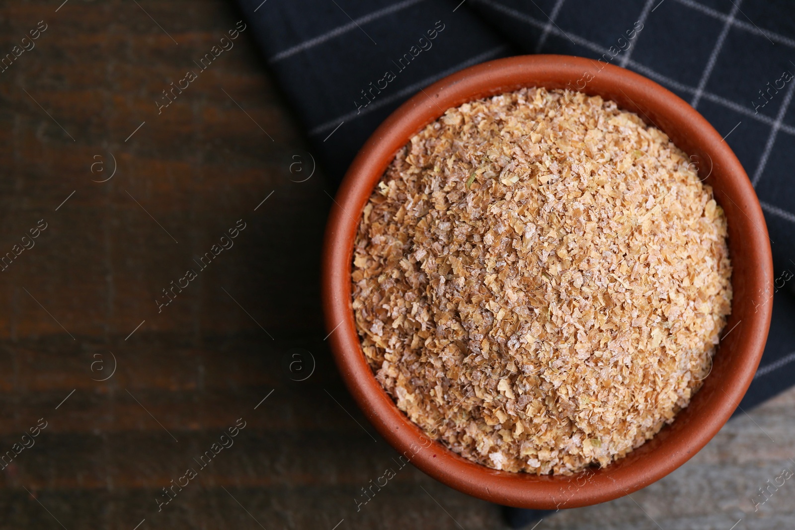 Photo of Buckwheat bran in bowl on wooden table, top view. Space for text