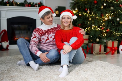 Lovely couple in Santa hats and Christmas sweaters at home