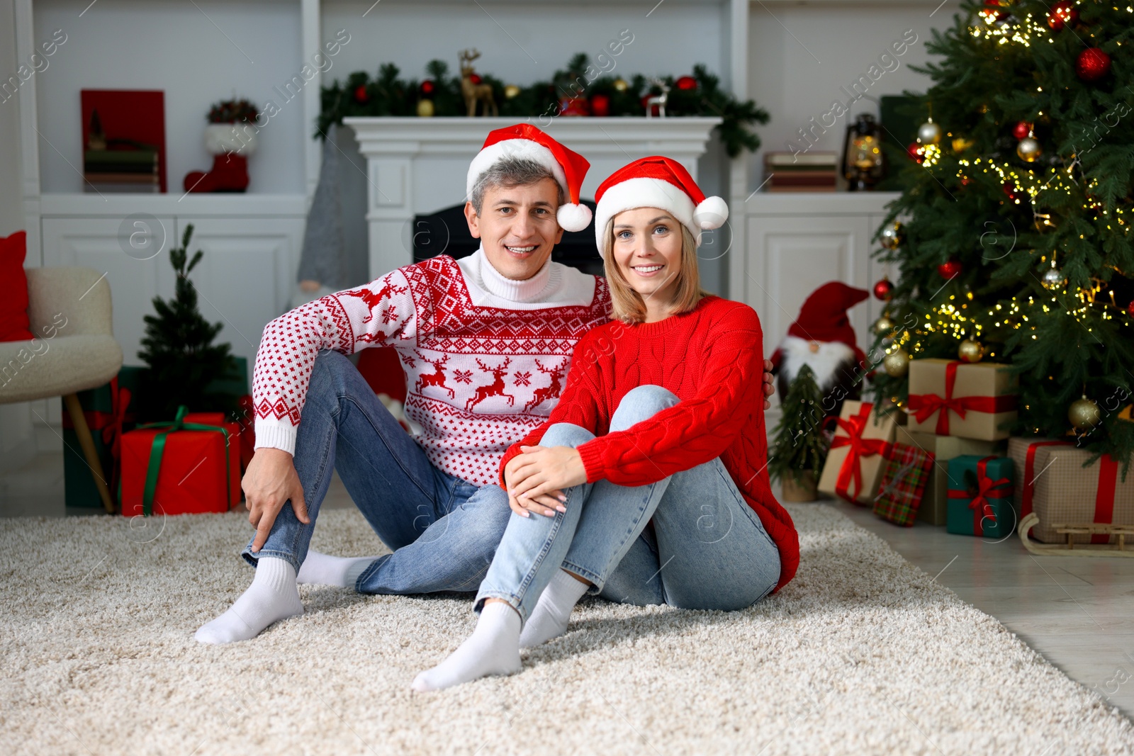 Photo of Lovely couple in Santa hats and Christmas sweaters at home