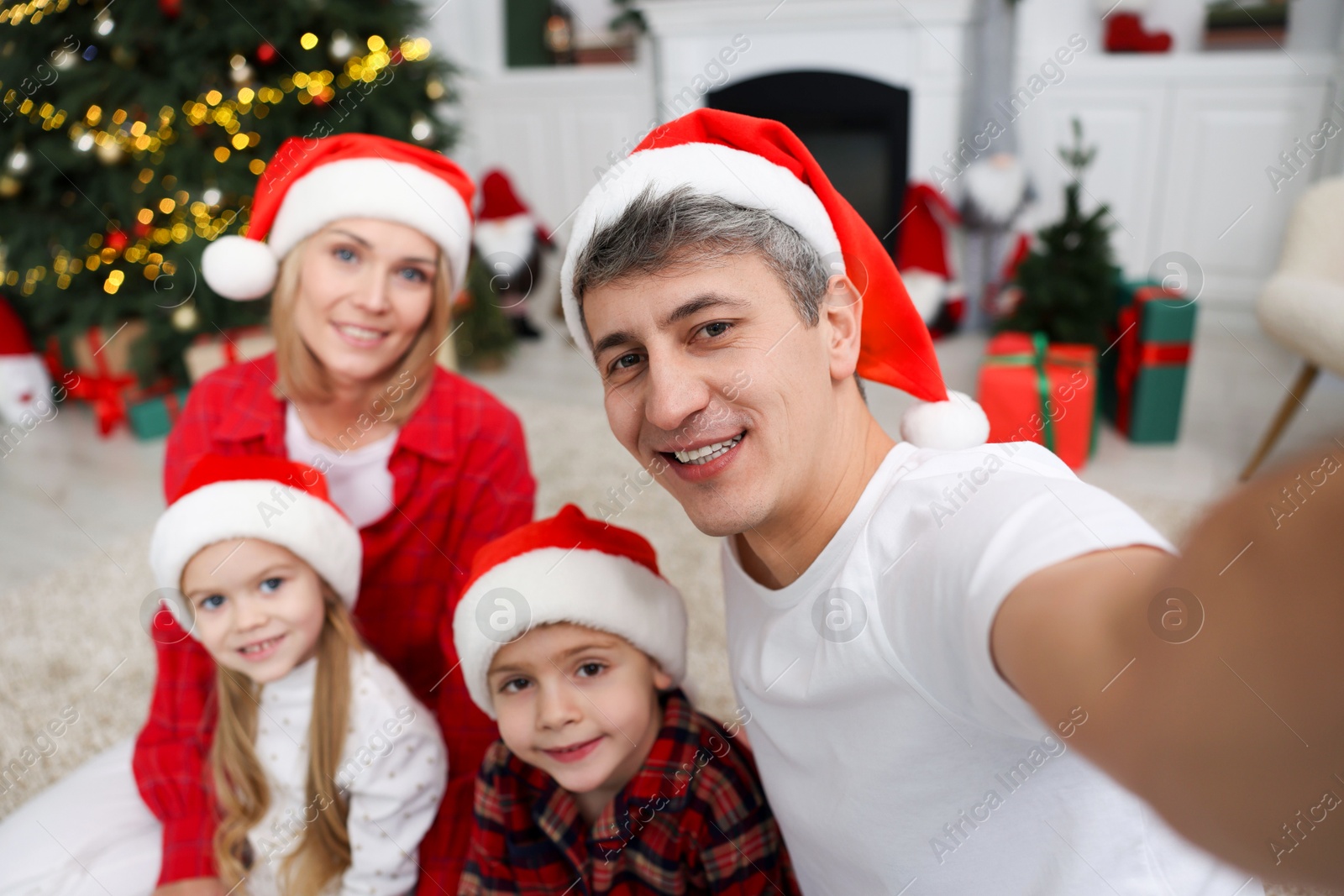 Photo of Happy family taking selfie together in Santa hats at home. Christmas season