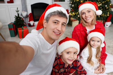 Photo of Happy family taking selfie together in Santa hats at home. Christmas season