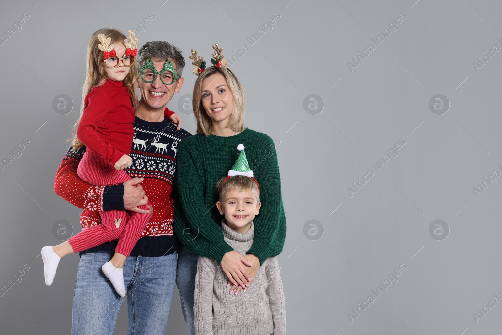 Photo of Happy family in Christmas sweaters and accessories on grey background. Space for text