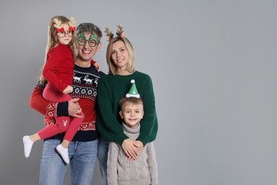 Happy family in Christmas sweaters and accessories on grey background. Space for text