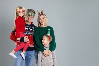 Photo of Happy family in Christmas sweaters and accessories on grey background. Space for text