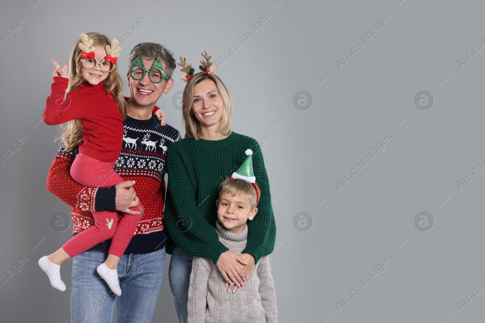 Photo of Happy family in Christmas sweaters and accessories on grey background. Space for text