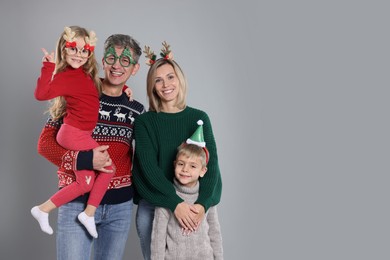 Happy family in Christmas sweaters and accessories on grey background. Space for text