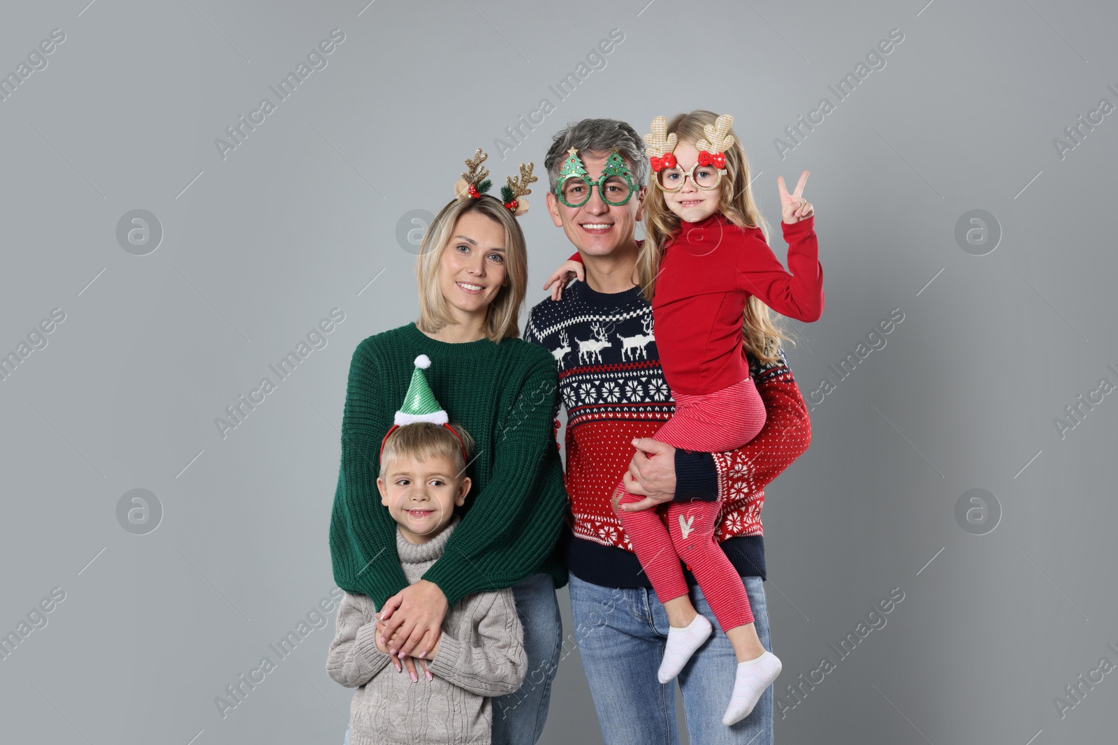 Photo of Happy family in Christmas sweaters and accessories on grey background