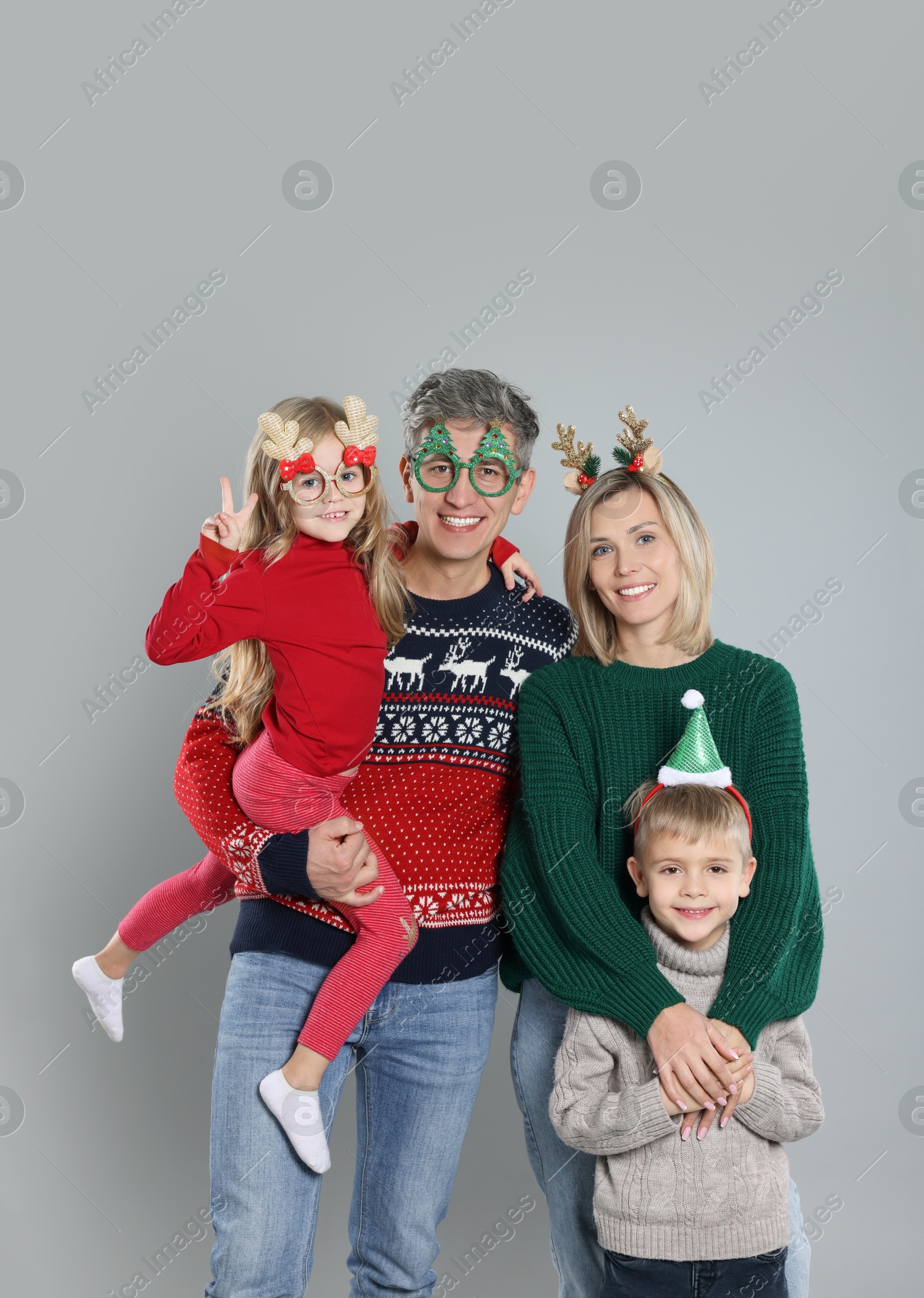 Photo of Happy family in Christmas sweaters and accessories on grey background