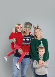 Happy family in Christmas sweaters and accessories on grey background