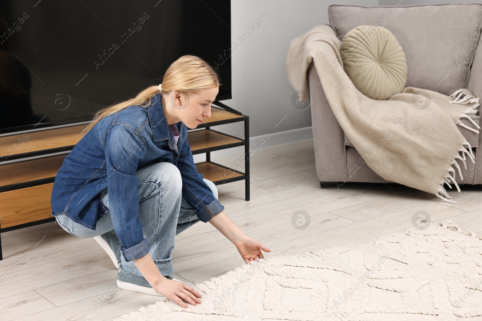 Photo of Female decorator placing beautiful carpet in room