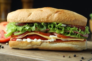 Photo of Delicious baguette sandwich with salami and cheese on wooden table