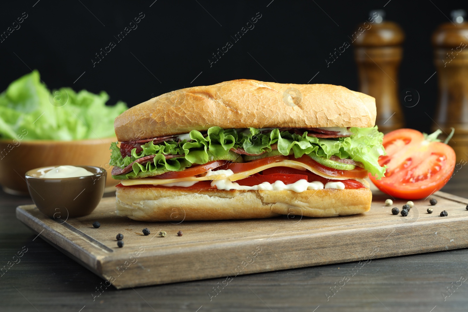 Photo of Delicious baguette sandwich with salami and cheese on grey wooden table