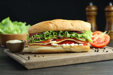 Photo of Delicious baguette sandwich with salami and cheese on grey wooden table