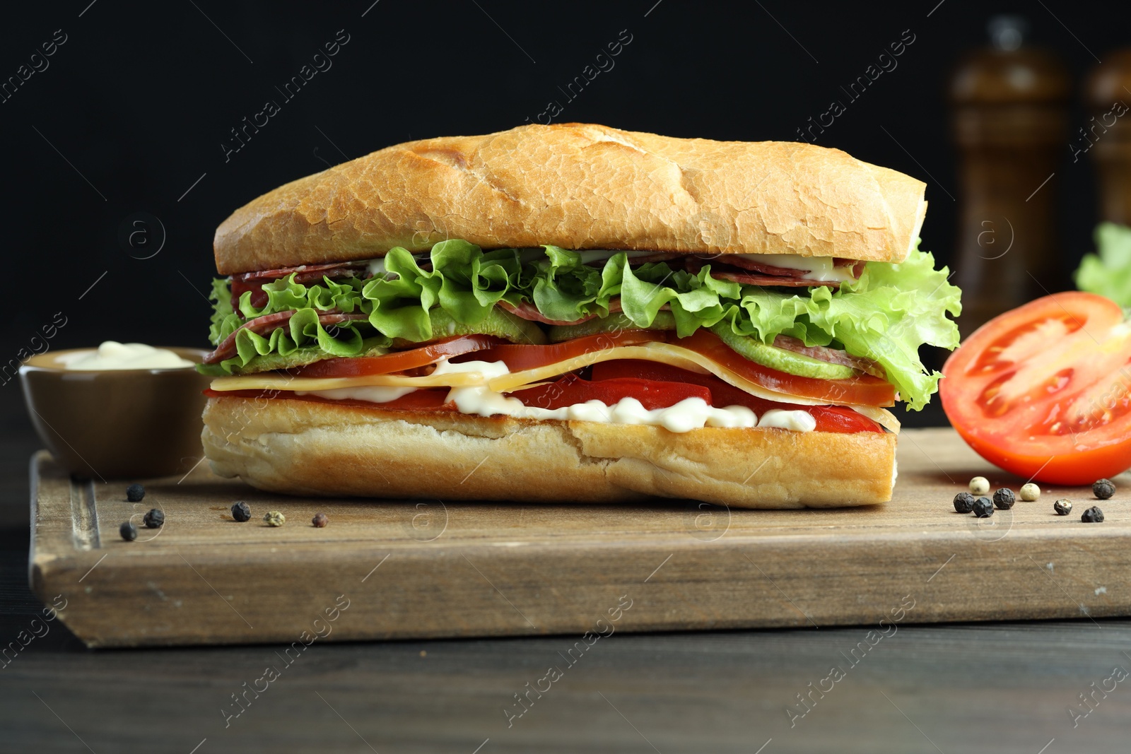 Photo of Delicious baguette sandwich with salami and cheese on grey wooden table