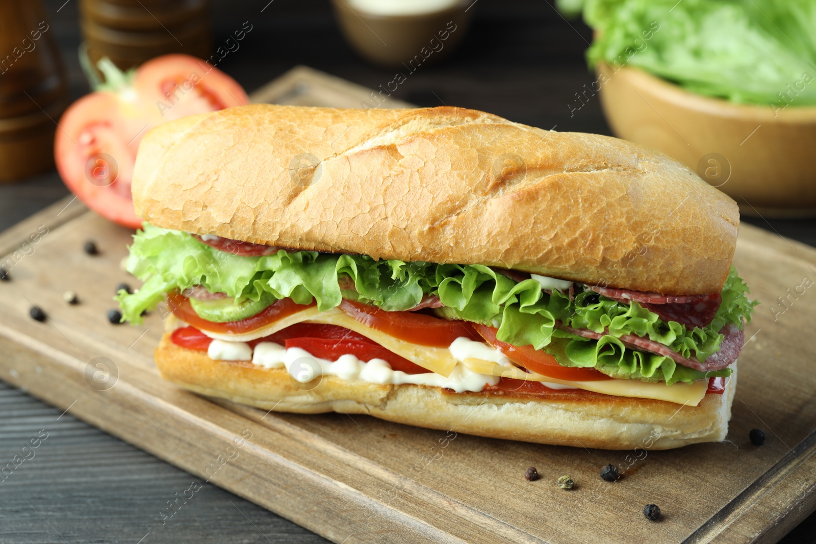 Photo of Delicious baguette sandwich with salami and cheese on grey wooden table, closeup