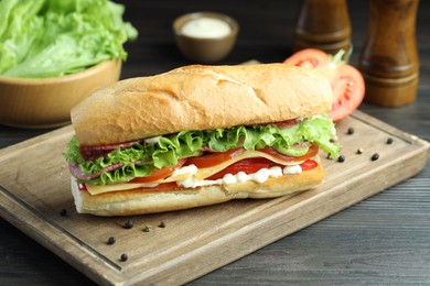 Photo of Delicious baguette sandwich with salami and cheese on grey wooden table, closeup