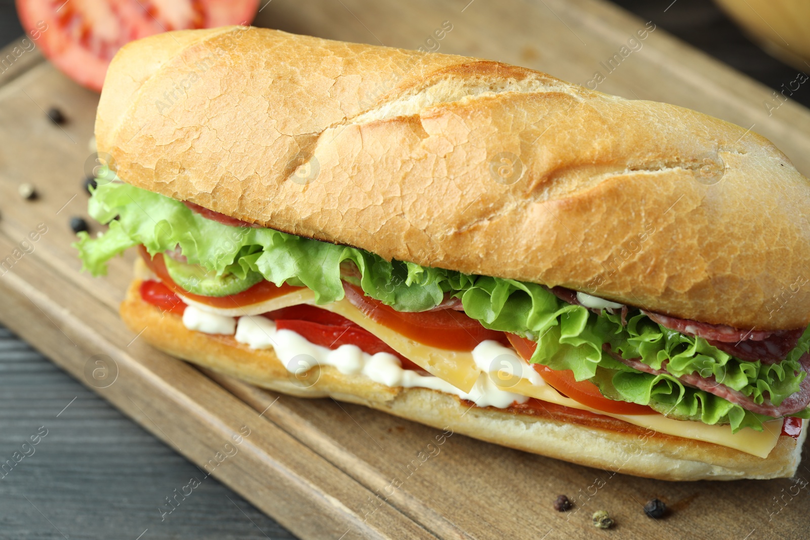 Photo of Delicious baguette sandwich with salami and cheese on table, closeup