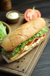 Photo of Delicious baguette sandwich with salami and cheese on grey wooden table