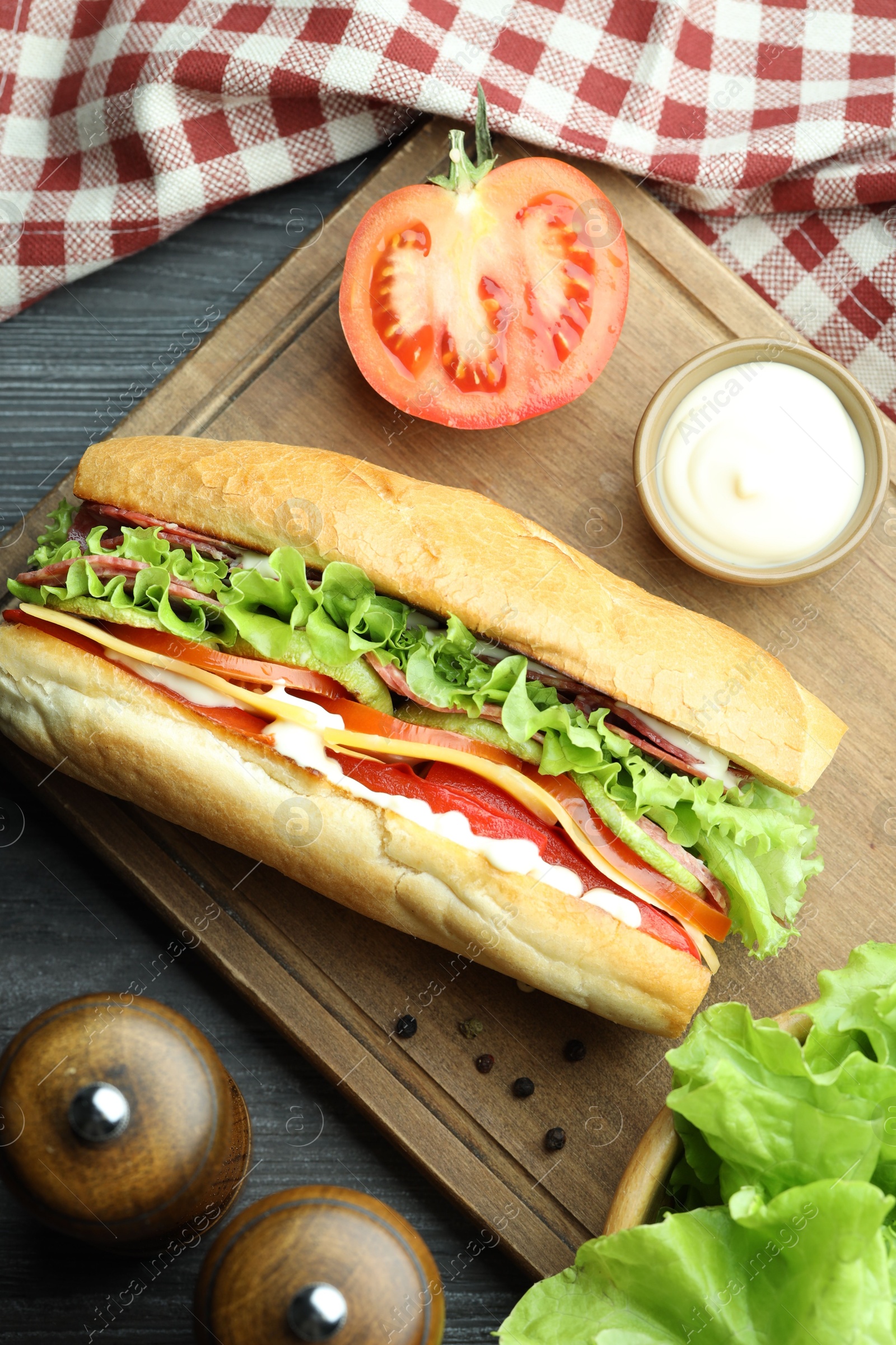 Photo of Delicious baguette sandwich with salami and cheese on grey wooden table, flat lay