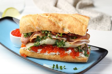 Photo of Delicious baguette sandwich with caviar, ham and capers on white wooden table, closeup