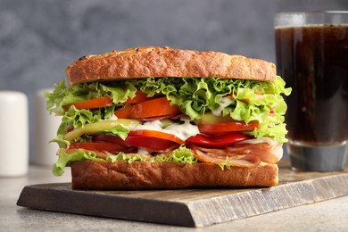 Photo of Delicious baguette sandwich with tomatoes and yellow beans on grey textured table, closeup