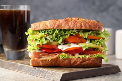 Photo of Delicious baguette sandwich with tomatoes and yellow beans on grey textured table, closeup