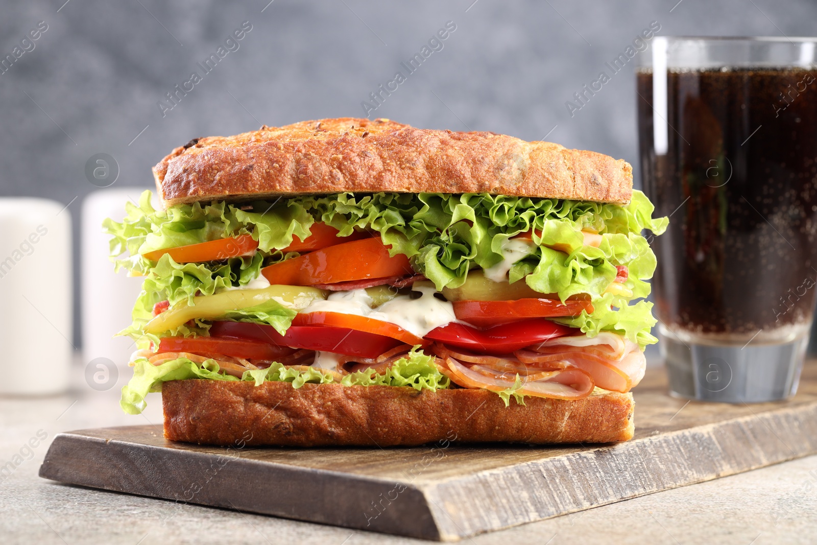 Photo of Delicious baguette sandwich with tomatoes and yellow beans on grey textured table, closeup