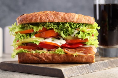 Photo of Delicious baguette sandwich with tomatoes and yellow beans on grey textured table, closeup