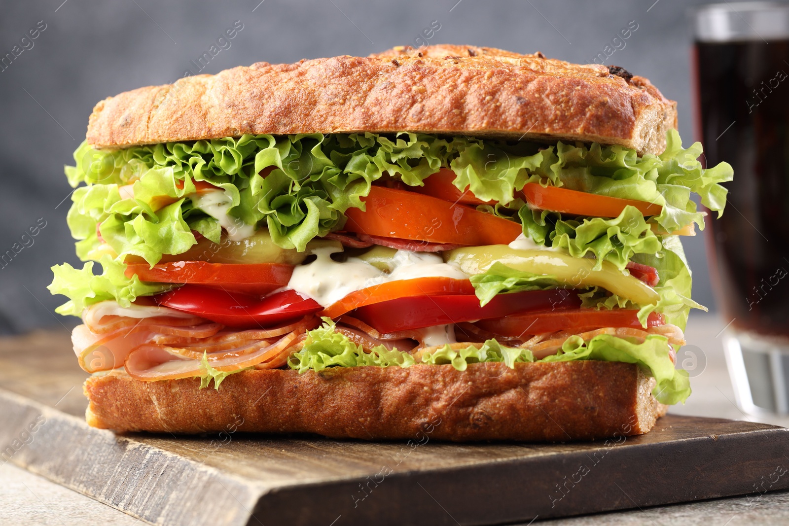 Photo of Delicious baguette sandwich with tomatoes and yellow beans on grey textured table, closeup