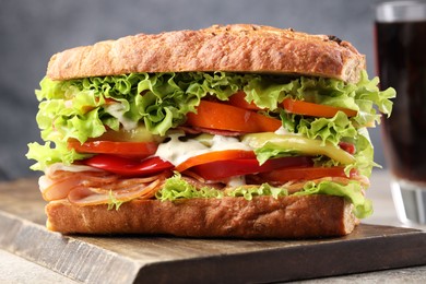 Photo of Delicious baguette sandwich with tomatoes and yellow beans on grey textured table, closeup