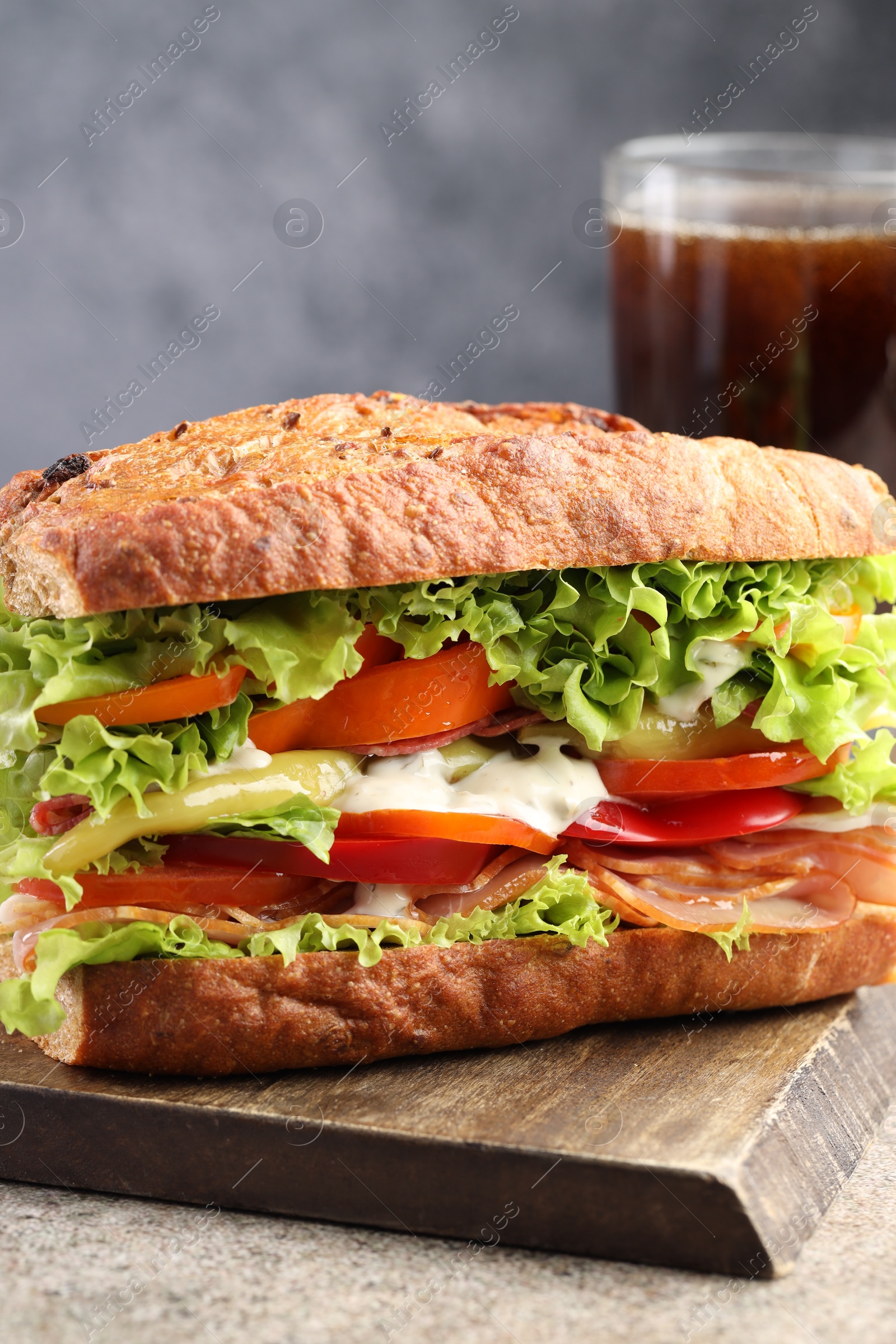 Photo of Delicious baguette sandwich with tomatoes and yellow beans on grey textured table, closeup