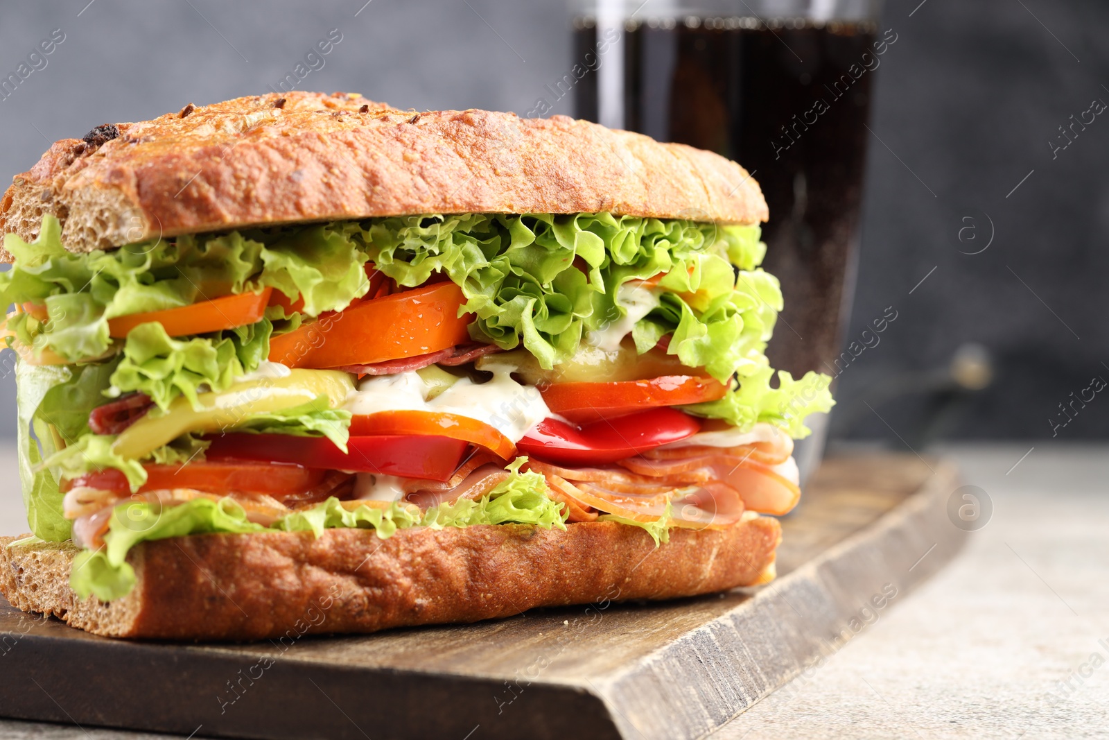 Photo of Delicious baguette sandwich with tomatoes and yellow beans on grey textured table, closeup