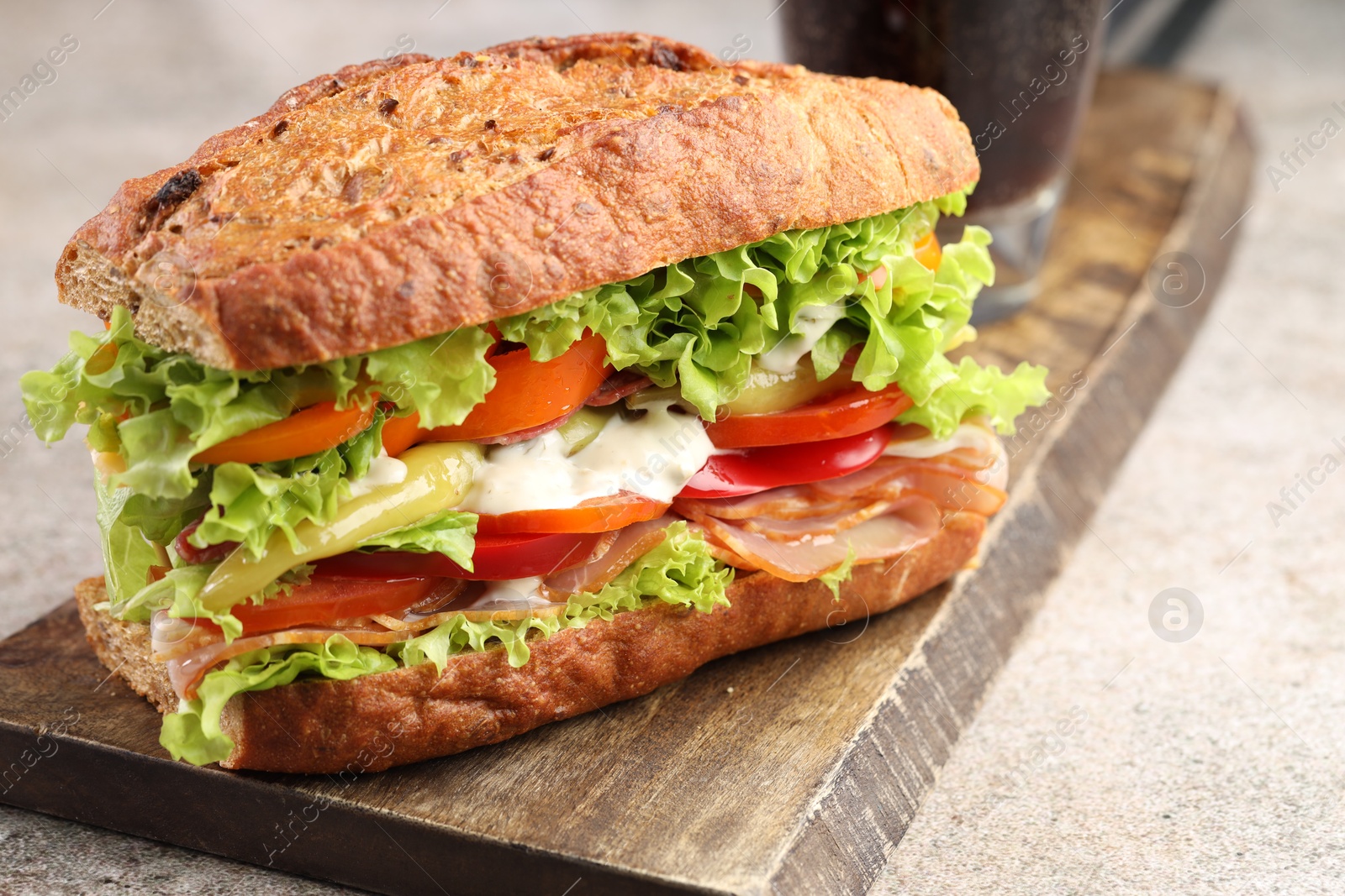 Photo of Delicious baguette sandwich with tomatoes and yellow beans on grey textured table, closeup