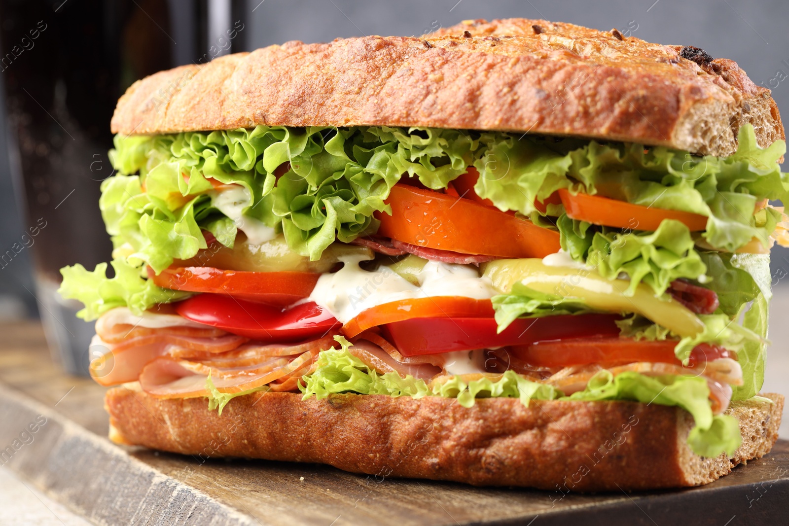 Photo of Delicious baguette sandwich with tomatoes and yellow beans on table, closeup