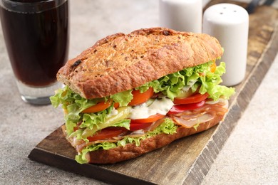 Photo of Delicious baguette sandwich with tomatoes and yellow beans on grey textured table, closeup