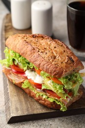 Photo of Delicious baguette sandwich with tomatoes and yellow beans on grey textured table, closeup