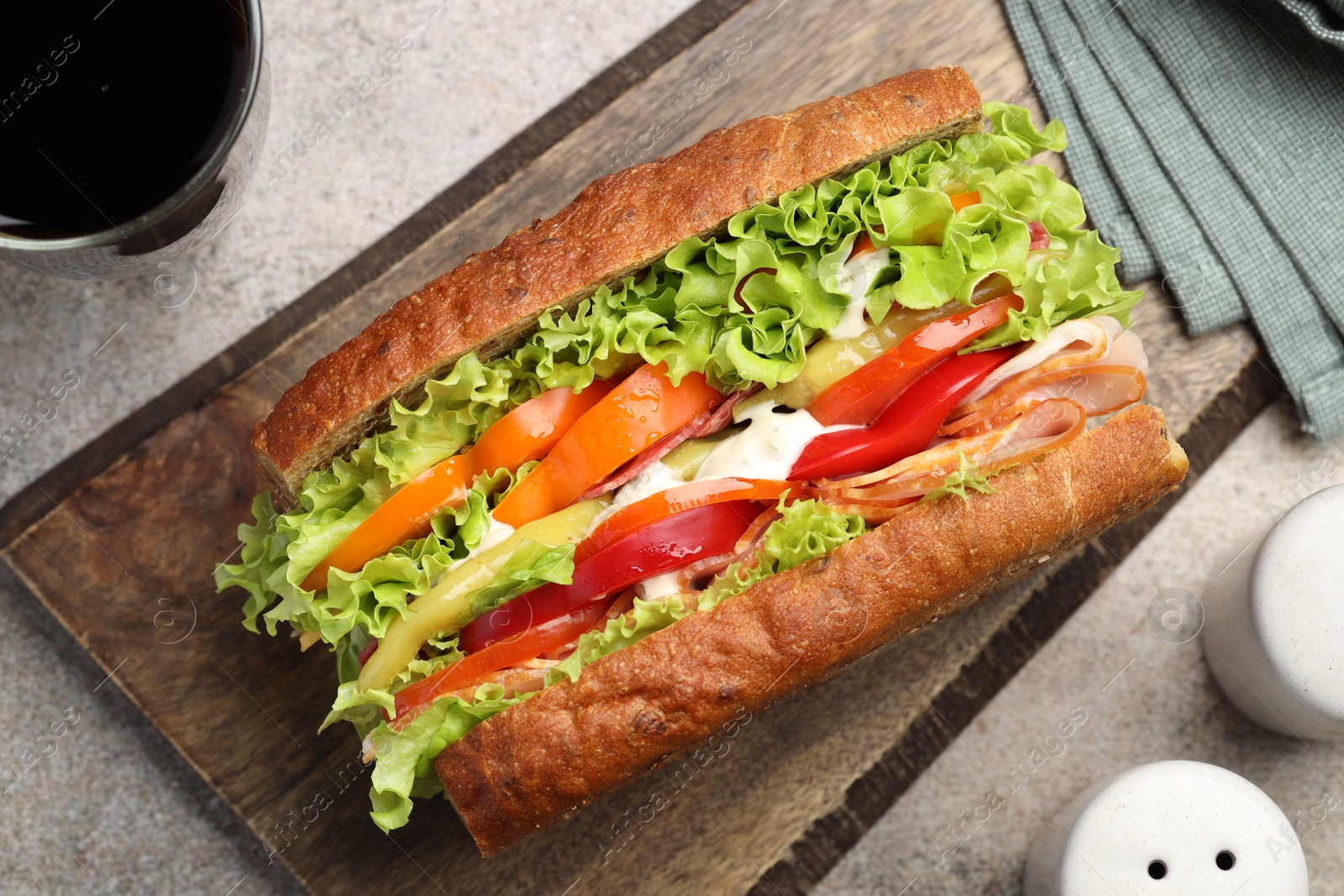 Photo of Delicious baguette sandwich with tomatoes and yellow beans on grey textured table, top view