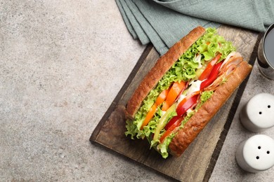 Photo of Delicious baguette sandwich with tomatoes and yellow beans on grey textured table, top view. Space for text