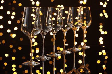 Photo of Empty wineglasses on mirror surface against dark background with blurred lights. Bokeh effect