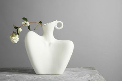 Photo of Stylish vase with snowberry branch on white table. Space for text