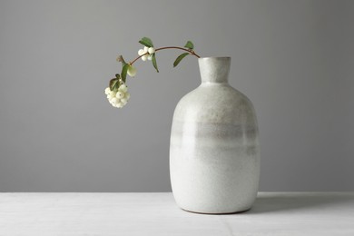 Photo of Stylish vase with snowberry branch on white table