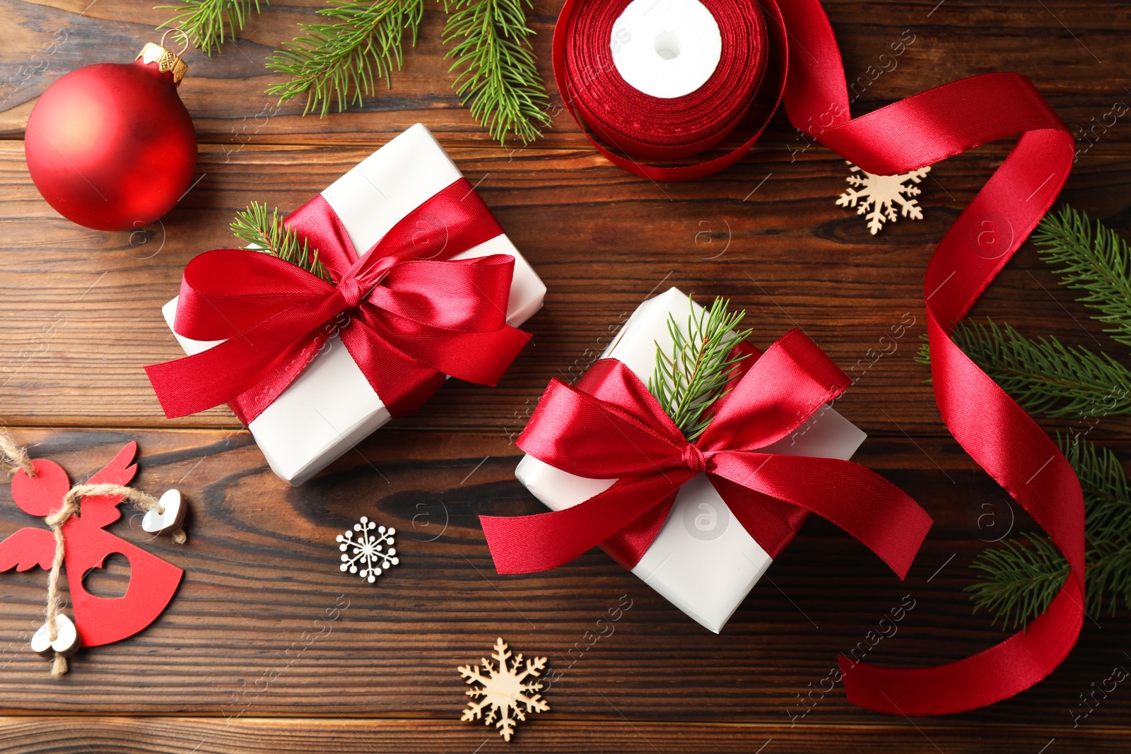 Photo of Beautiful gift boxes, ribbon and Christmas decor on wooden table, flat lay