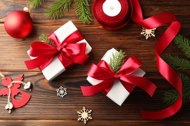 Photo of Beautiful gift boxes, ribbon and Christmas decor on wooden table, flat lay