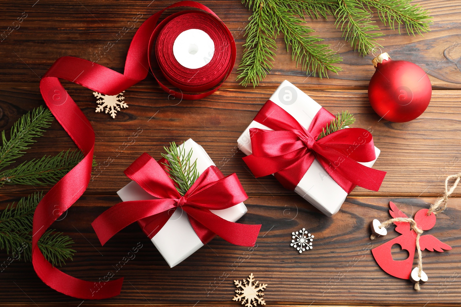 Photo of Beautiful gift boxes, ribbon and Christmas decor on wooden table, flat lay