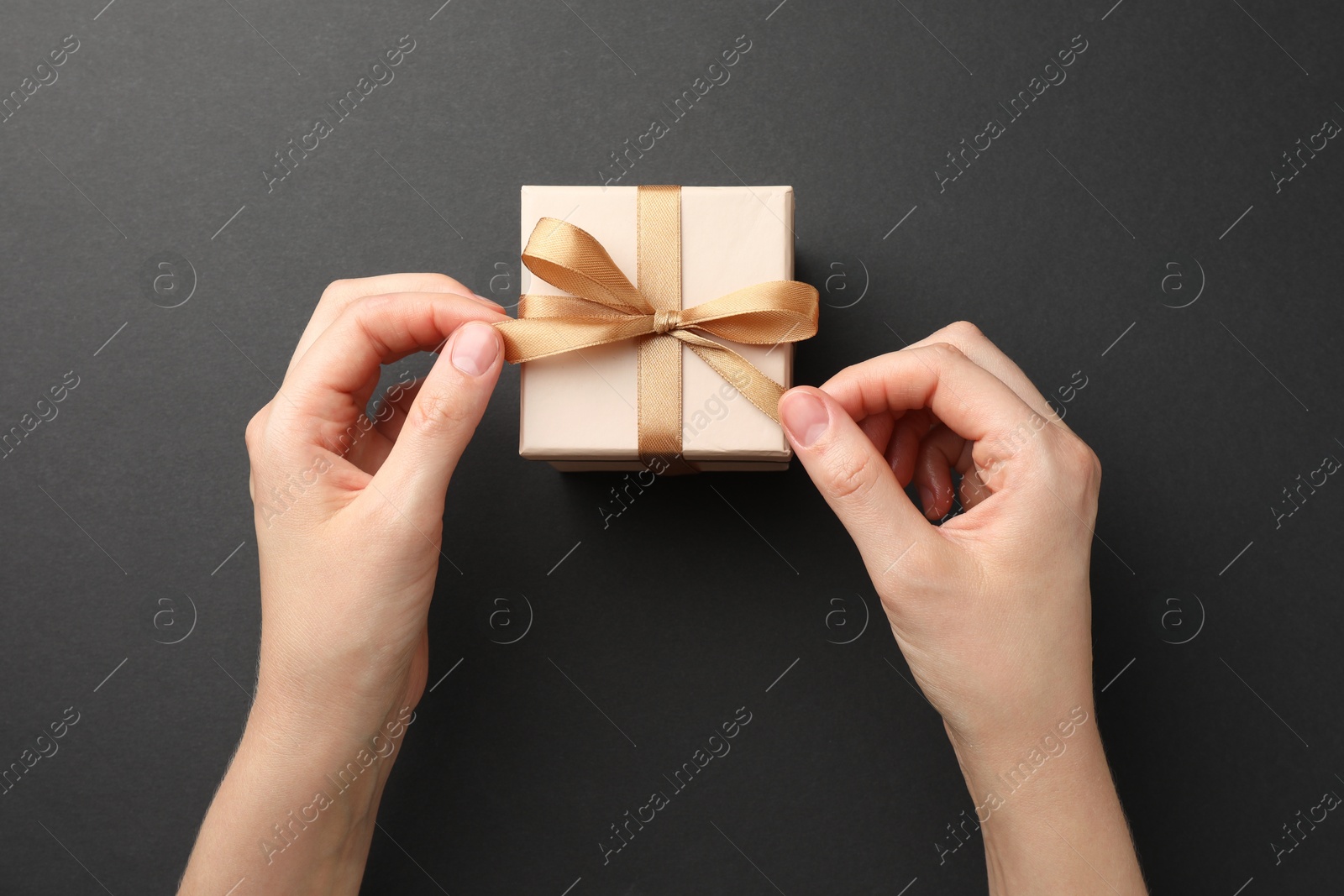 Photo of Woman opening gift box on black background, top view