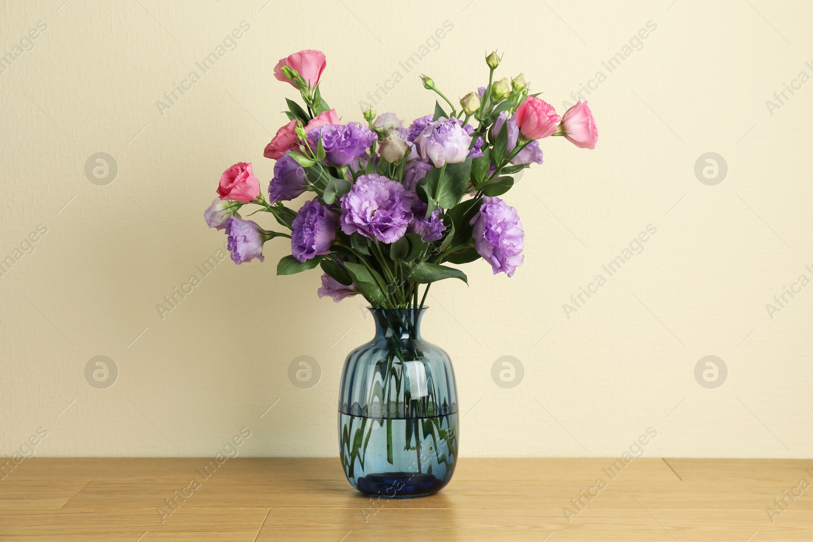 Photo of Vase with beautiful eustoma flowers on wooden table