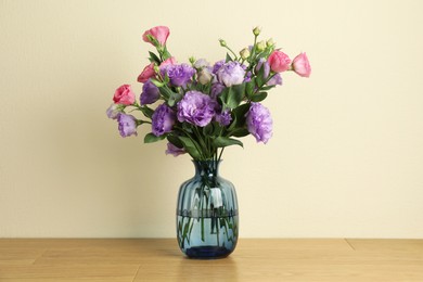 Photo of Vase with beautiful eustoma flowers on wooden table