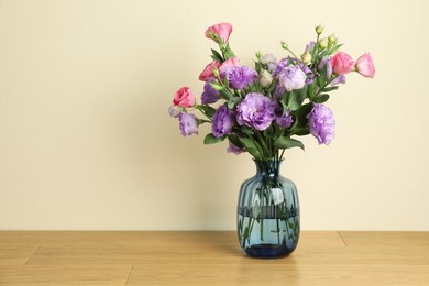 Photo of Vase with beautiful eustoma flowers on wooden table, space for text