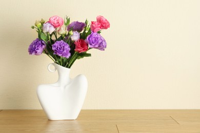 Photo of Vase with beautiful eustoma flowers on wooden table, space for text